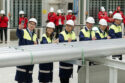 executives stand behind a row of aluminum billets in an aluminum casthouse for a signing ceremony